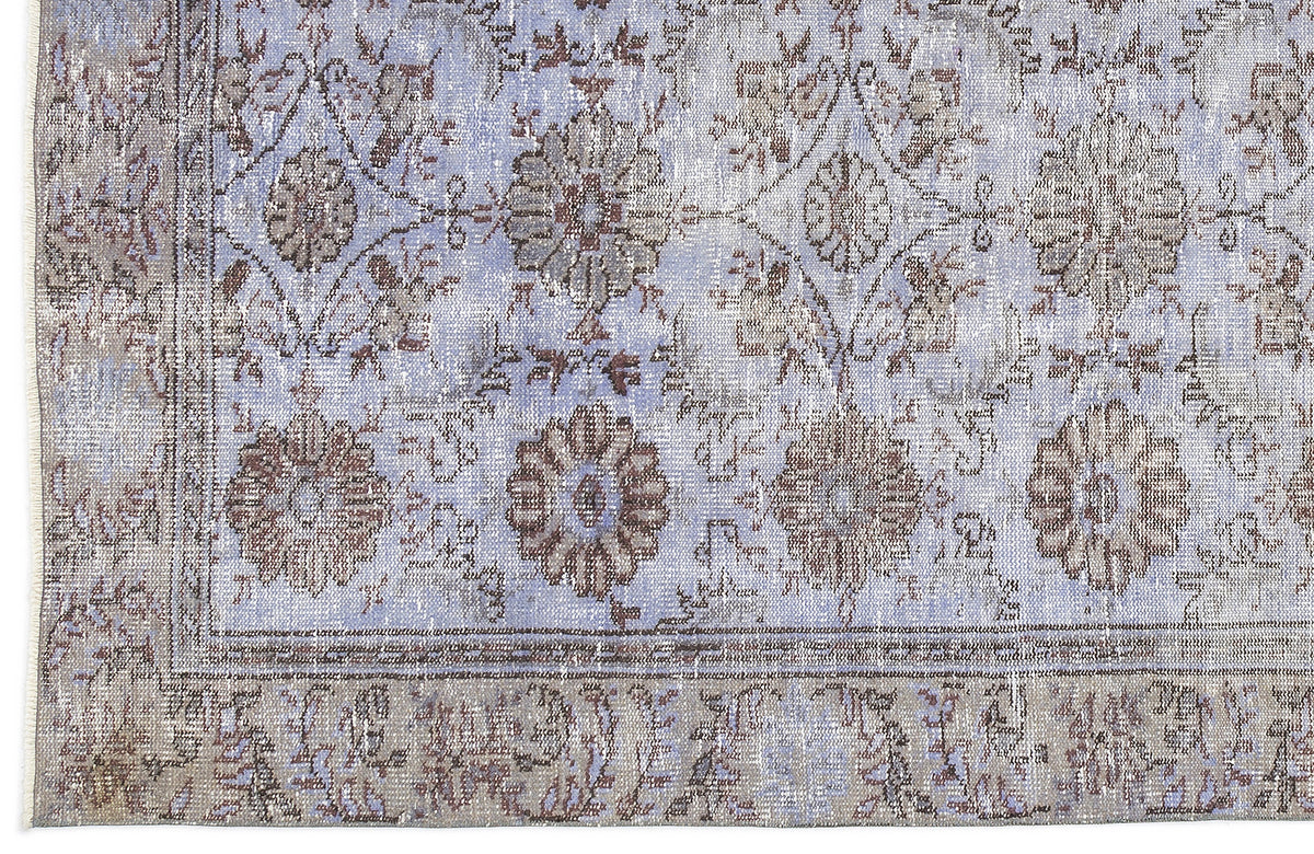 Periwinkle and taupe vintage-style rug with a distressed floral medallion pattern and a decorative border.