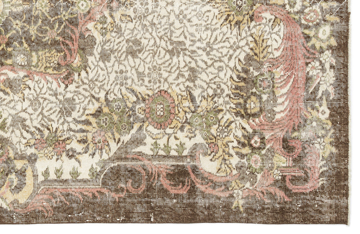 Distressed brown, cream, and muted pink rug with a traditional floral medallion pattern and a wide border.
