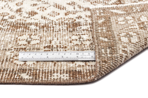 Load image 1 in gallery view. Brown and cream distressed patterned rug with a folded corner and a metal ruler for scale.