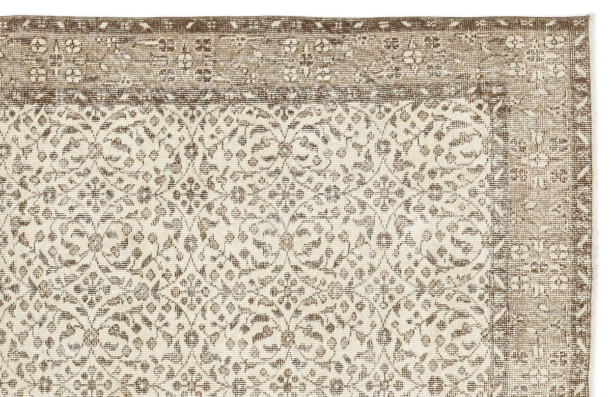 Beige and brown rug with a distressed, repeating floral medallion pattern and a decorative border.
