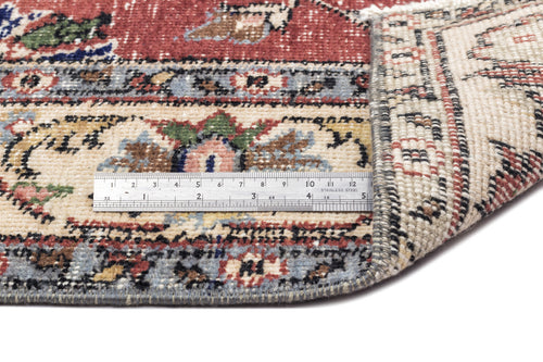 Load image 1 in gallery view. Red, cream, and blue traditional floral rug with a folded corner and a metal ruler for scale.