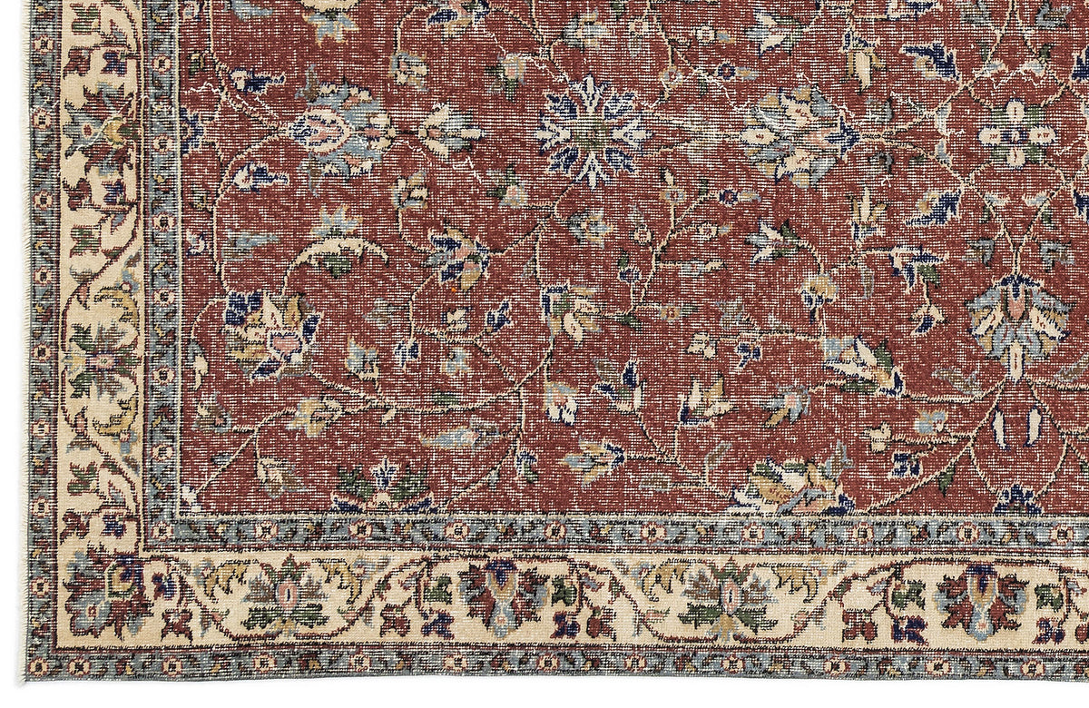 Terracotta red traditional rug with a floral vine pattern and a cream border featuring intricate botanical motifs.