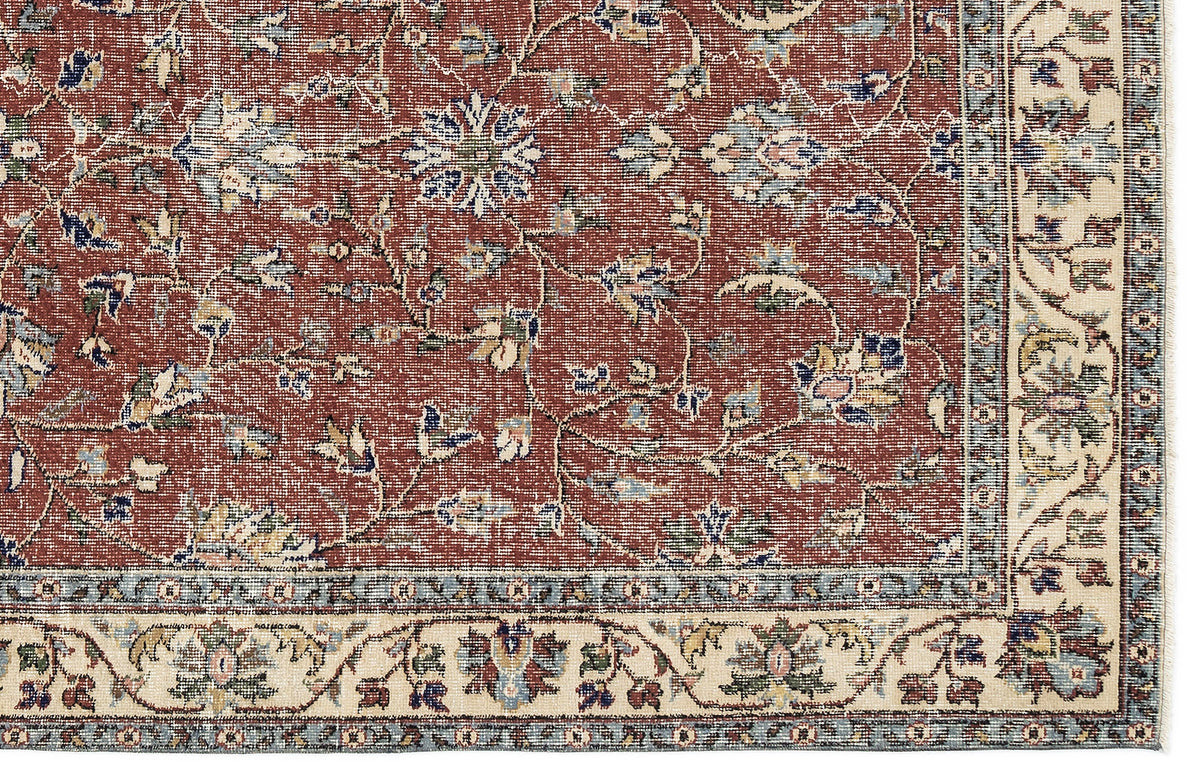 Terracotta rug with a traditional floral vine pattern, blue and cream accents, and a wide cream border.