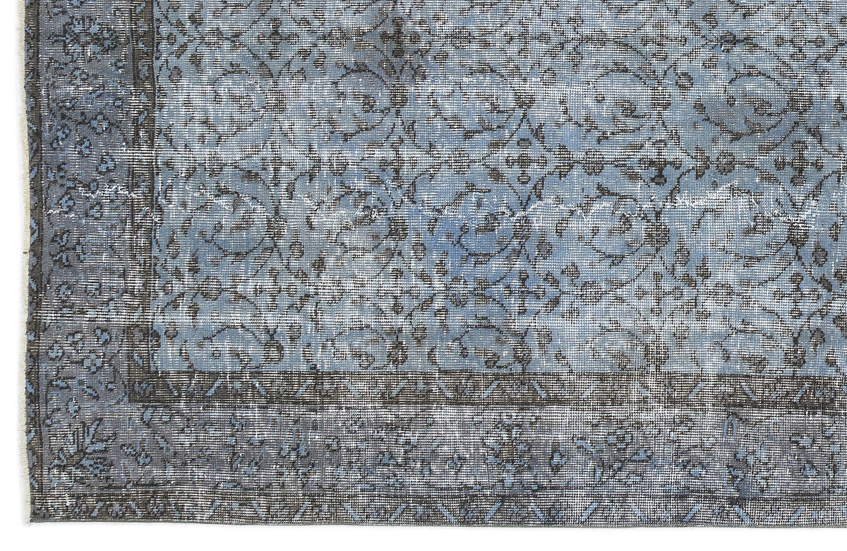 Blue and charcoal grey distressed rug with a traditional floral vine pattern and a wide geometric border.
