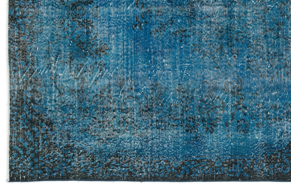 Teal and black distressed rug with a faded floral pattern and a dark border.