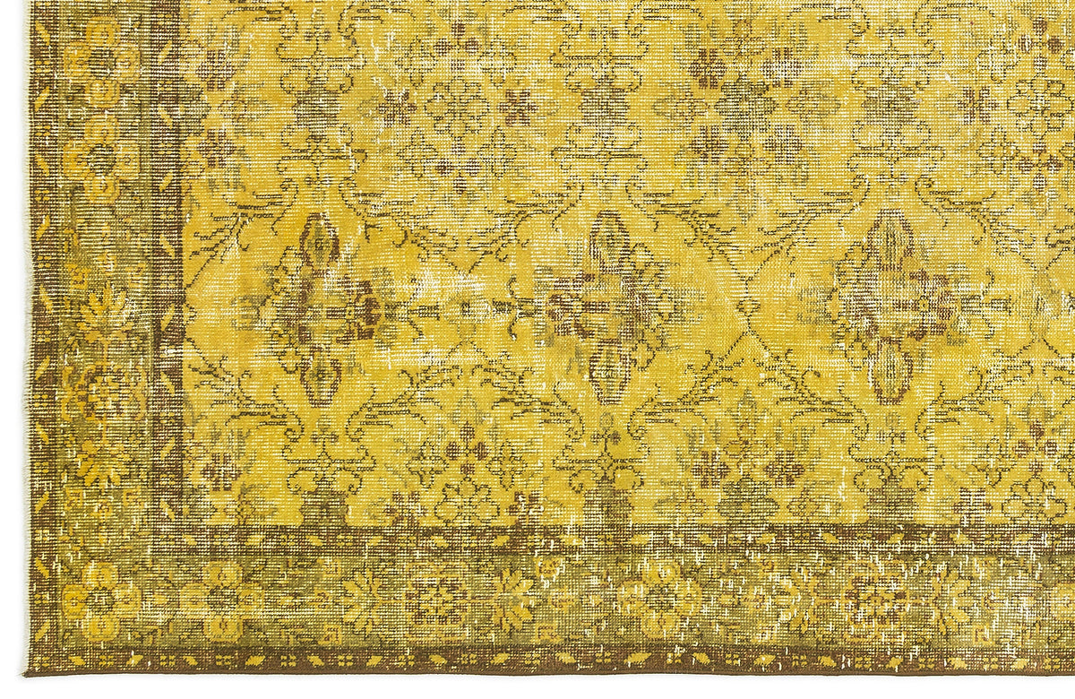 Mustard yellow and brown distressed rug with a traditional floral medallion pattern and a wide decorative border.