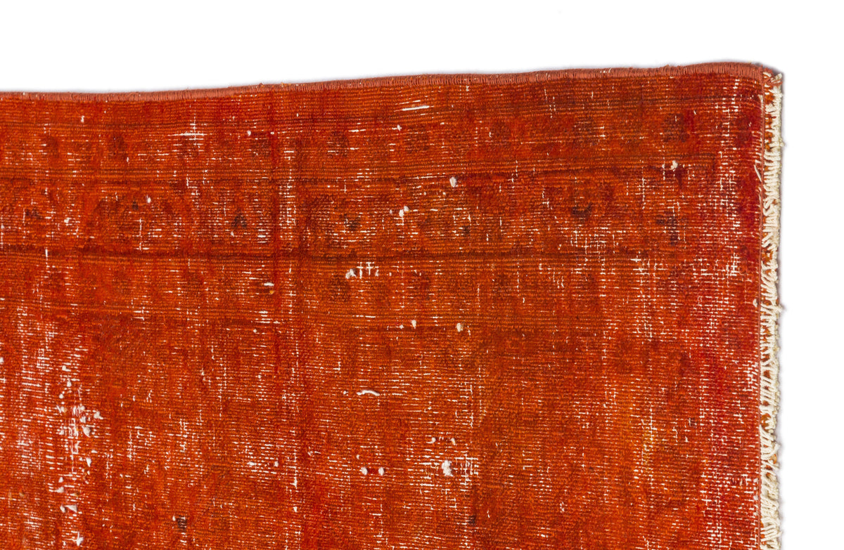 Distressed rust-orange rug with a faded geometric pattern and white fringe edge on a white background.