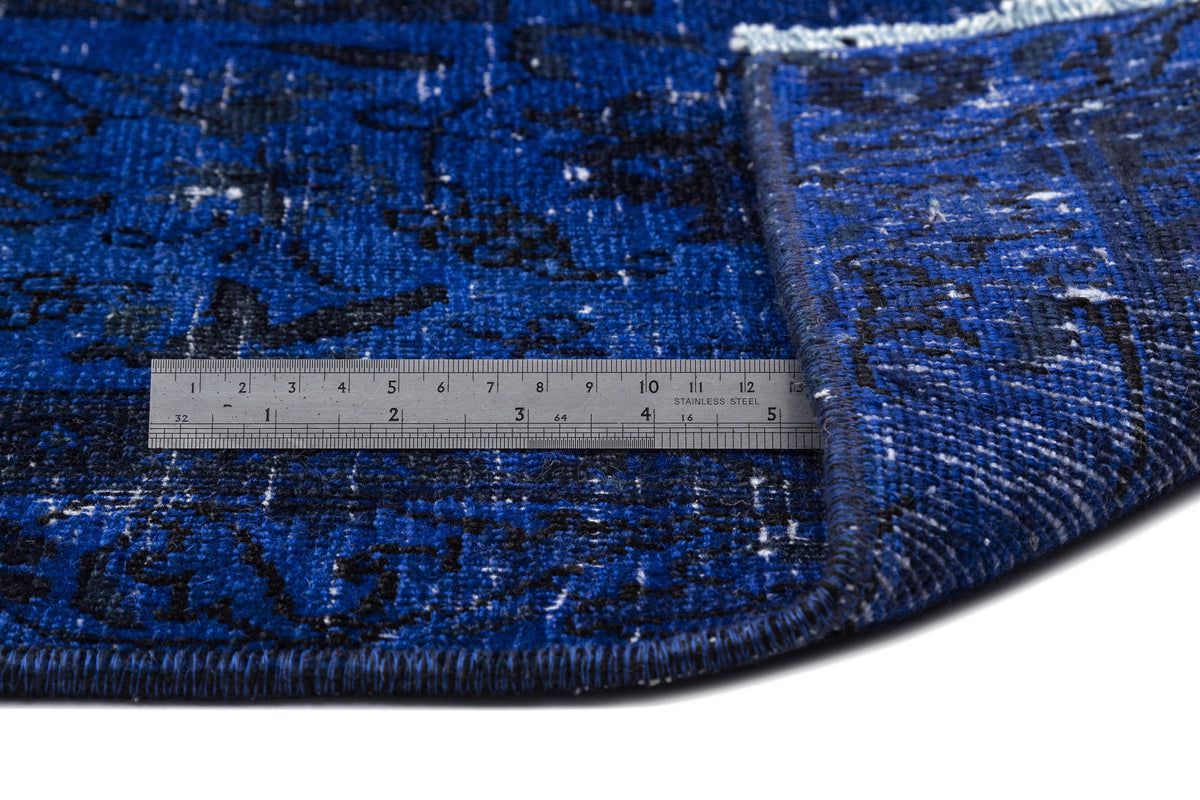 Blue and black distressed patterned rug with a folded corner and a metal ruler for scale.