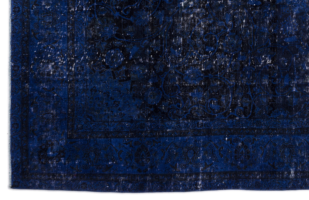 Deep blue and black distressed rug with a traditional floral medallion border and faded, worn-in texture.