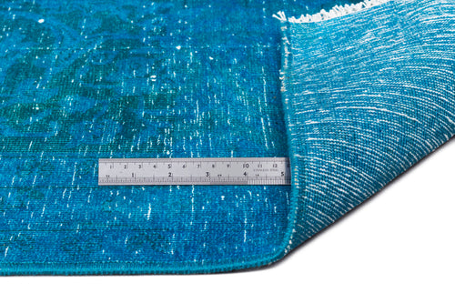 Load image 1 in gallery view. Distressed teal rug with a faded traditional pattern, white fringe, and a metal ruler for scale on a white background.