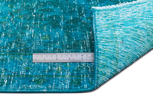 Load image 1 in gallery view. Teal and white distressed-pattern rug with a folded corner and a metal ruler for scale on a white background.