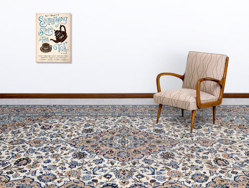 Load image 1 in gallery view. Cream, blue, and tan traditional Persian-style rug with a central floral medallion, styled in a room with an armchair.