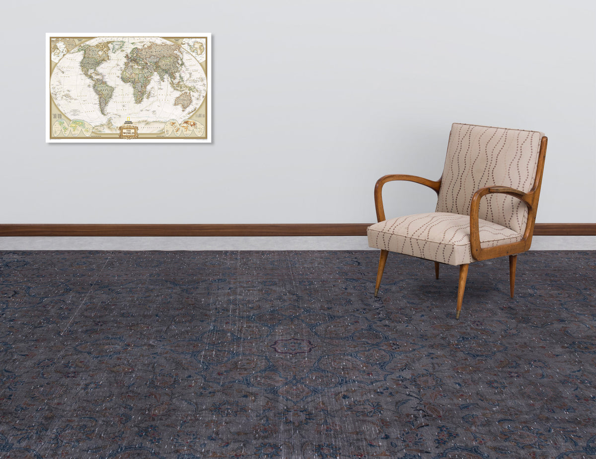 Dark grey distressed rug with a traditional floral medallion pattern, styled in a room with a patterned armchair.