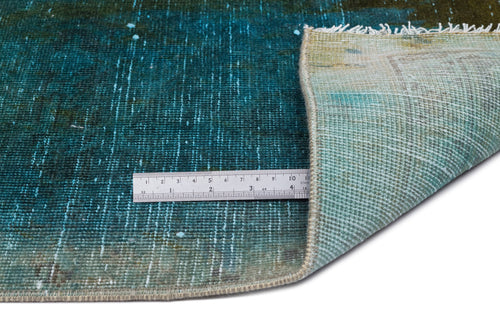 Load image 1 in gallery view. Teal and olive green distressed rug with a folded corner and a metal ruler for scale on a white background.