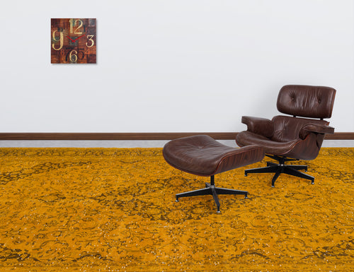 Load image 1 in gallery view. Mustard yellow rug with a dark brown distressed floral pattern, styled in a room with a leather lounge chair.