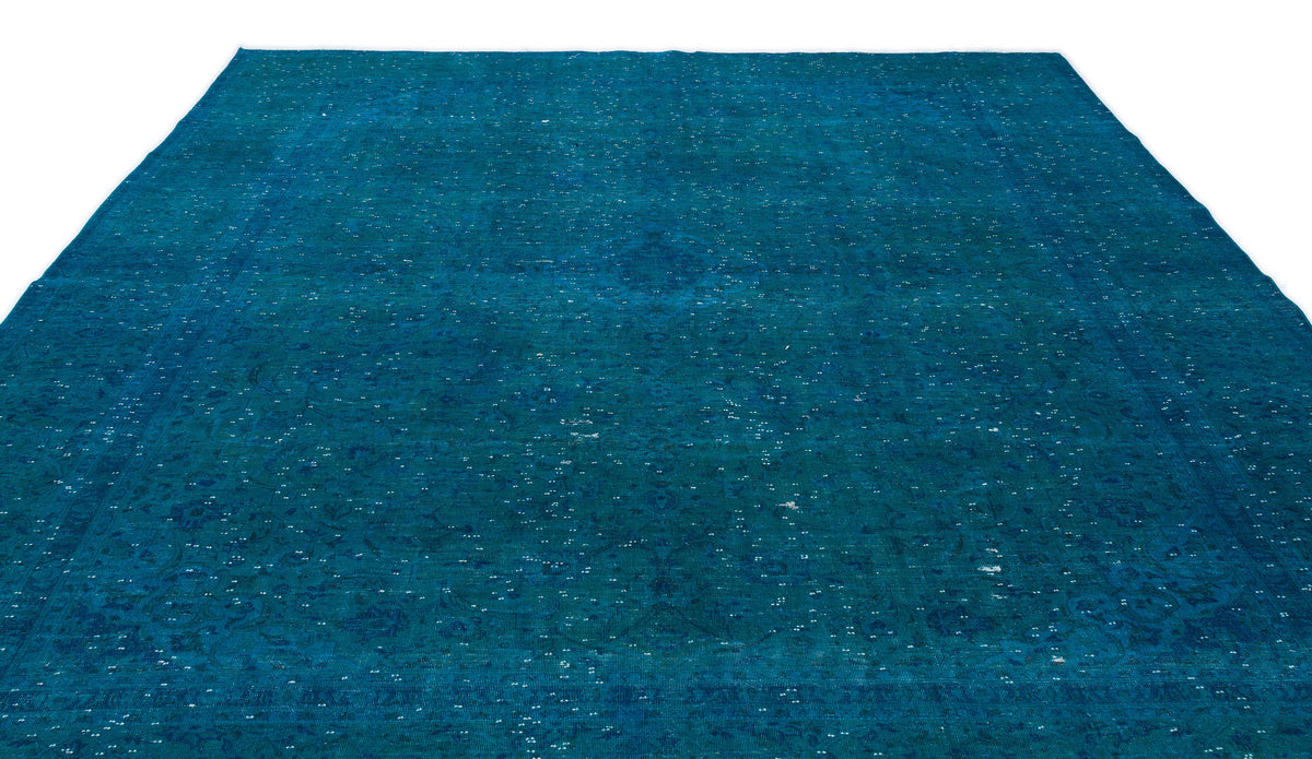 Deep teal distressed rug with a faint traditional medallion pattern and scattered white highlights.