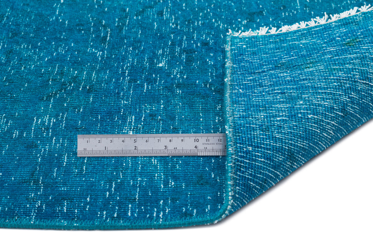 Teal distressed rug with white flecked texture and white fringe, shown with a metal ruler for scale.