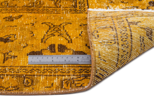 Load image 1 in gallery view. Mustard yellow and brown distressed rug with a geometric pattern, shown folded with a metal ruler for scale.