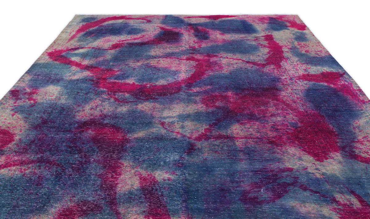 Distressed rug with an abstract, mottled pattern in shades of magenta, deep blue, and cream.