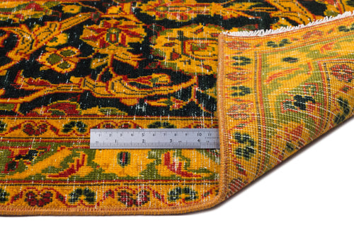 Load image 1 in gallery view. Traditional rug with black, yellow, and green floral pattern, shown folded with a metal ruler for scale.