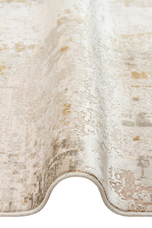 Load image 1 in gallery view. Cream, beige, and gold abstract distressed rug with a folded edge on a white background.