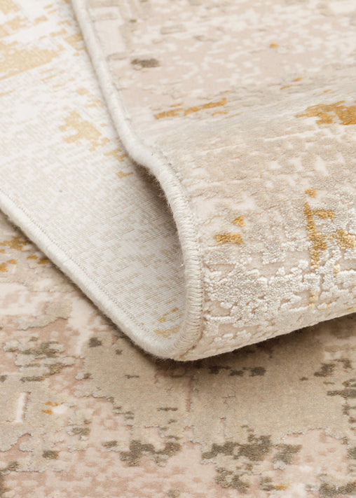 Beige and cream area rug with a distressed, abstract pattern and a serged edge, shown in a close-up folded view.