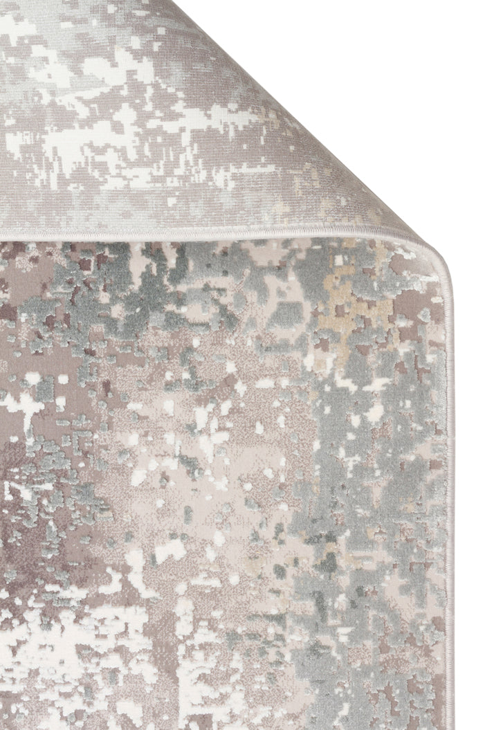 Mauve, grey, and cream area rug with a distressed, pixelated abstract pattern, shown with a corner folded over.