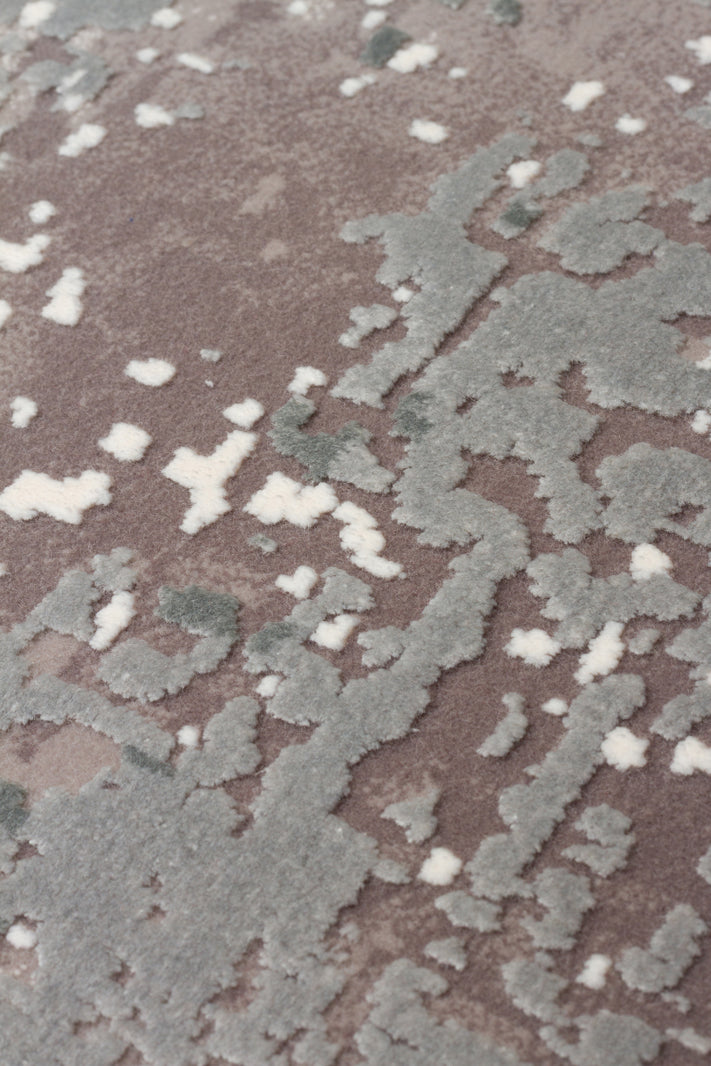 Close-up of a taupe rug with a raised, textured abstract pattern in sage green and cream.