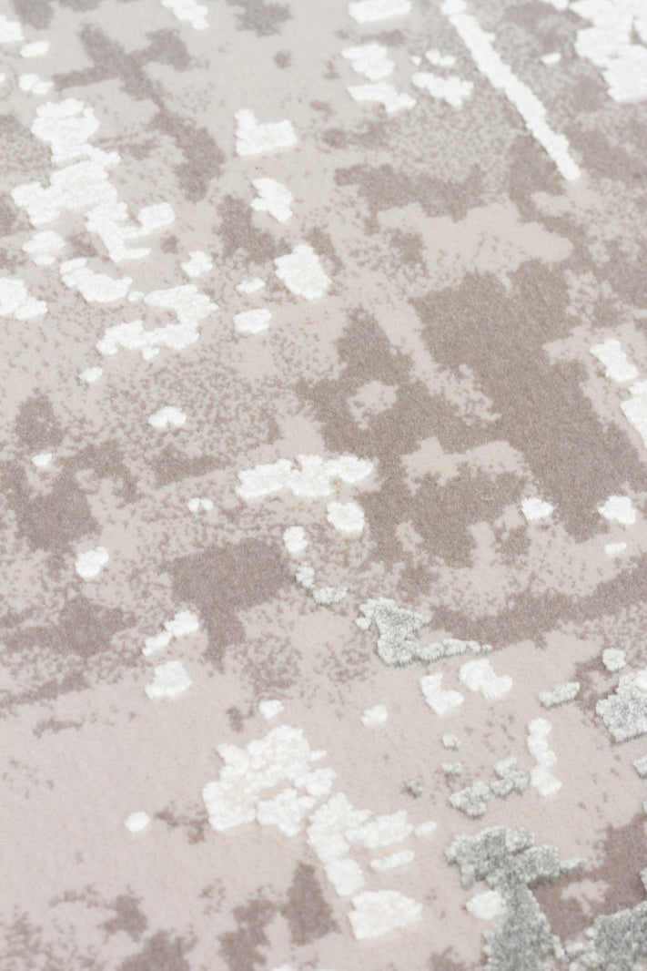 Taupe and white rug with a distressed, abstract mottled pattern and high-low pile texture.
