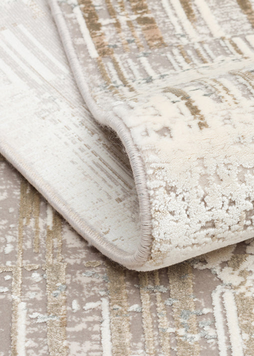 Cream and beige rug with a distressed abstract pattern, shown folded to reveal the texture and serged edge.