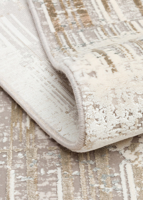 Load image 1 in gallery view. Cream and beige rug with a distressed abstract pattern, shown folded to reveal the texture and serged edge.