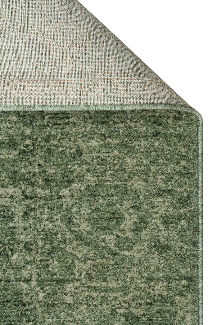 Forest green rug with a distressed traditional medallion pattern, showing the woven backing and serged edge.