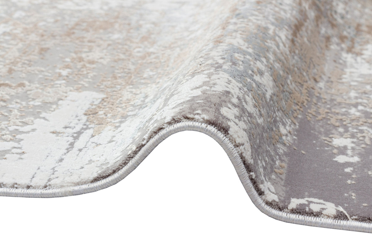 Grey, beige, and white abstract distressed rug with a serged edge, shown on a white background.