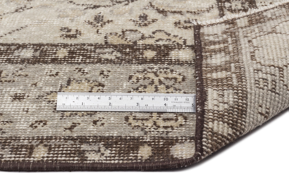 A close-up of the Kemora - Vintage Floral Rug (4'10 x 8'6) shows its beige and brown floral patterns. A ruler displays the flatwoven thickness, and a folded corner reveals the underside, reflecting classic Anatolian heritage craftsmanship.