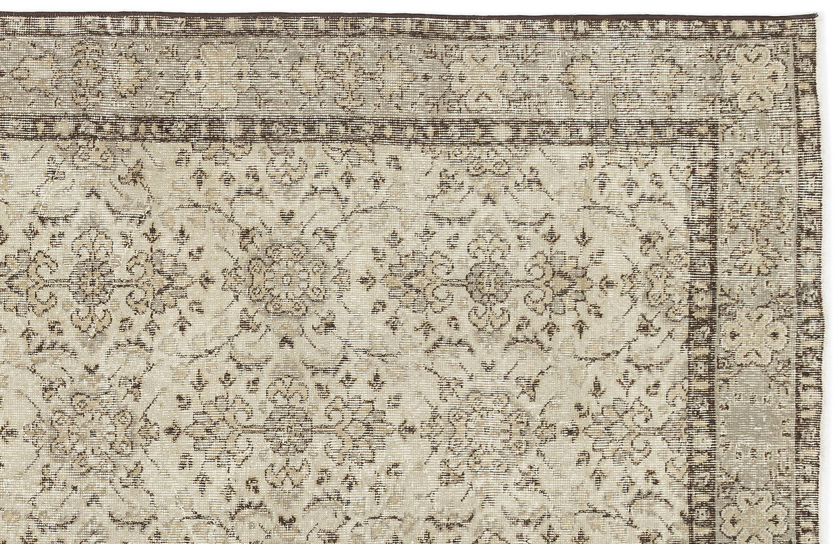 A close-up of the Kemora - Vintage Floral Rug (4'10 X 8'6) shows its beige and brown tones, ornate faded floral and vine pattern, decorative border, and vintage distressed design.