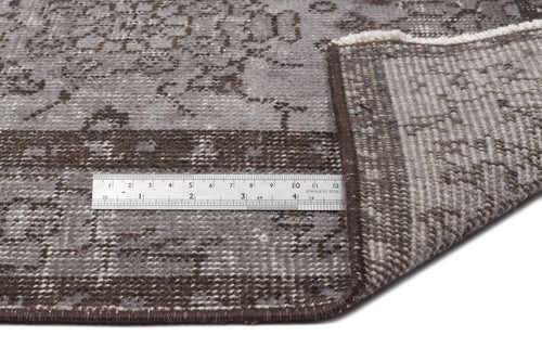 Load image 1 in gallery view. Grey and brown distressed medallion rug with a folded corner and a stainless steel ruler for scale.