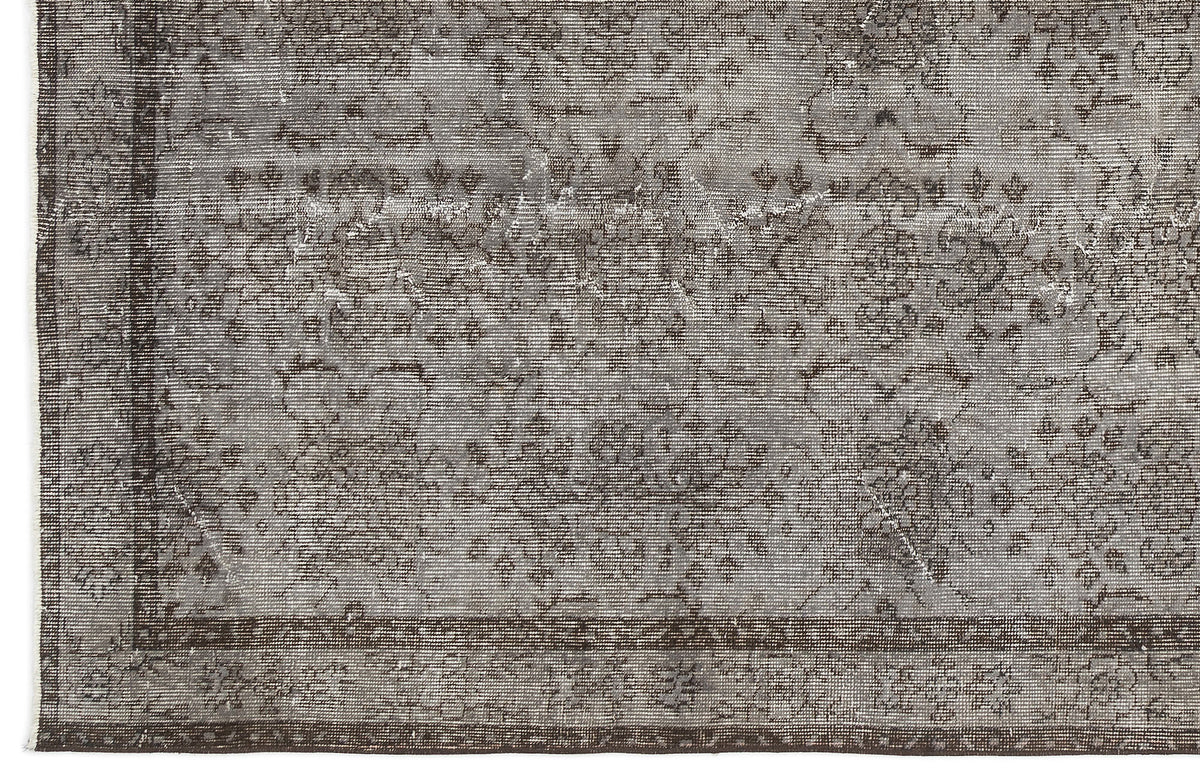 Grey and charcoal distressed rug with a faded traditional floral medallion pattern and a dark border.