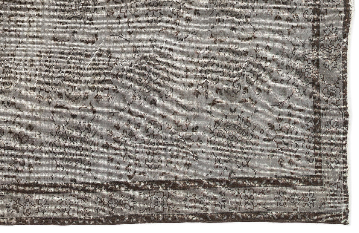 Grey and brown distressed rug with a traditional floral medallion pattern and a wide decorative border.