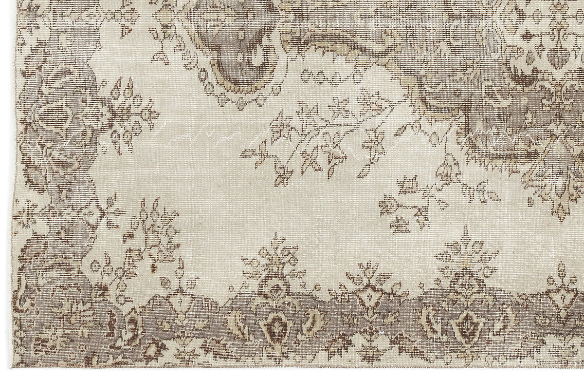 A close-up of the Luboane - Vintage Medallion Rug (6'1 X 9'1) shows its beige and taupe palette, ornate border, floral motifs, and a faded Anatolian-inspired vintage look.