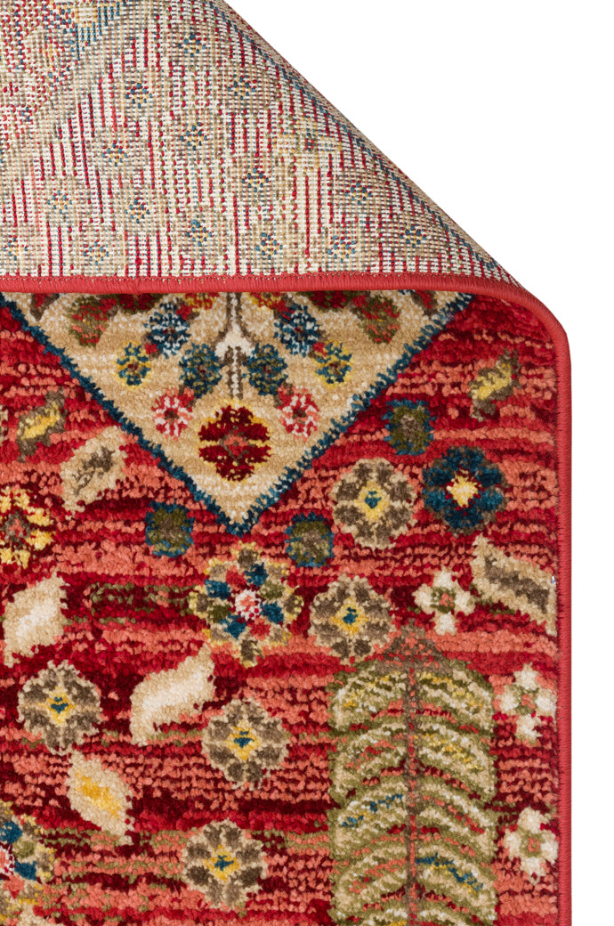 Red rug with a traditional floral medallion pattern, multi-colored botanical motifs, and a folded corner on white.