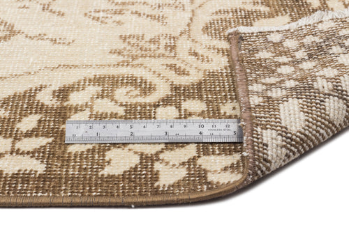Load image 1 in gallery view. Beige and cream floral patterned rug with a folded corner and a metal ruler for scale on a white background.