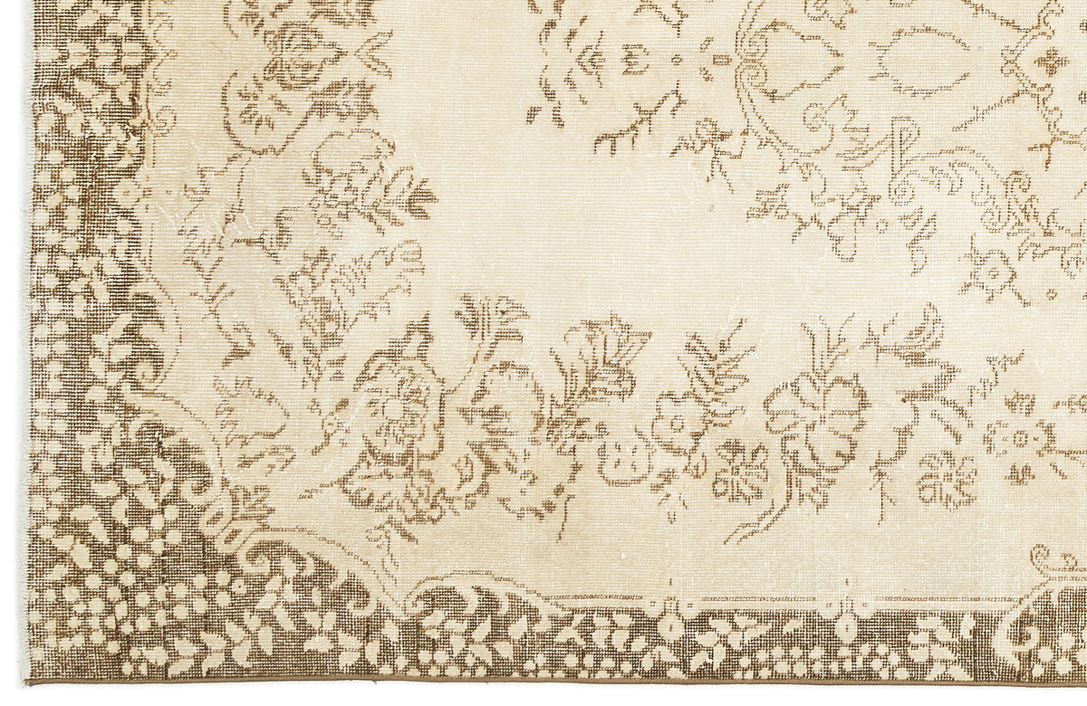 Cream and beige rug with a distressed floral medallion pattern and a detailed border.