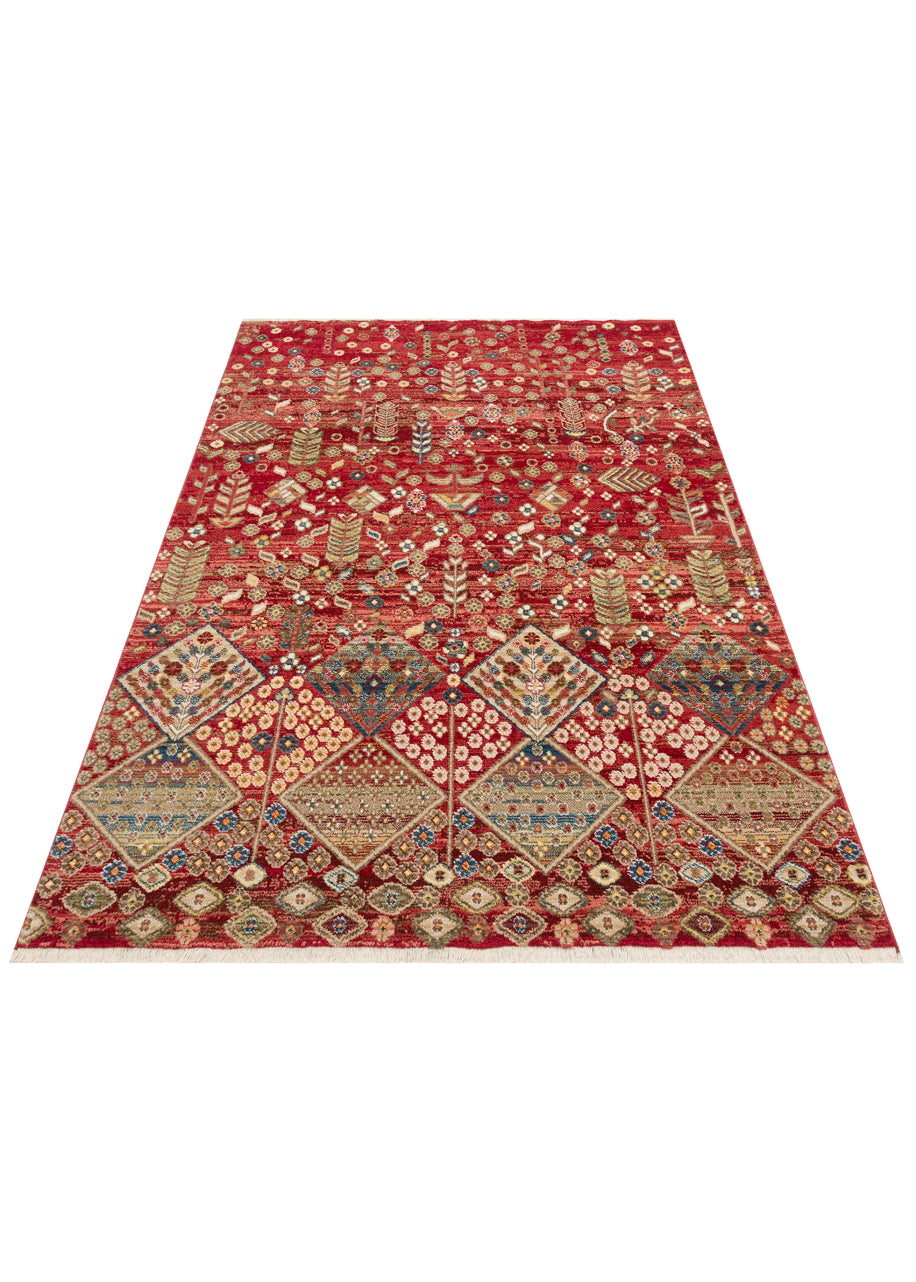 Red rug with a traditional floral and diamond pattern in blue, gold, and cream, featuring a fringed edge.