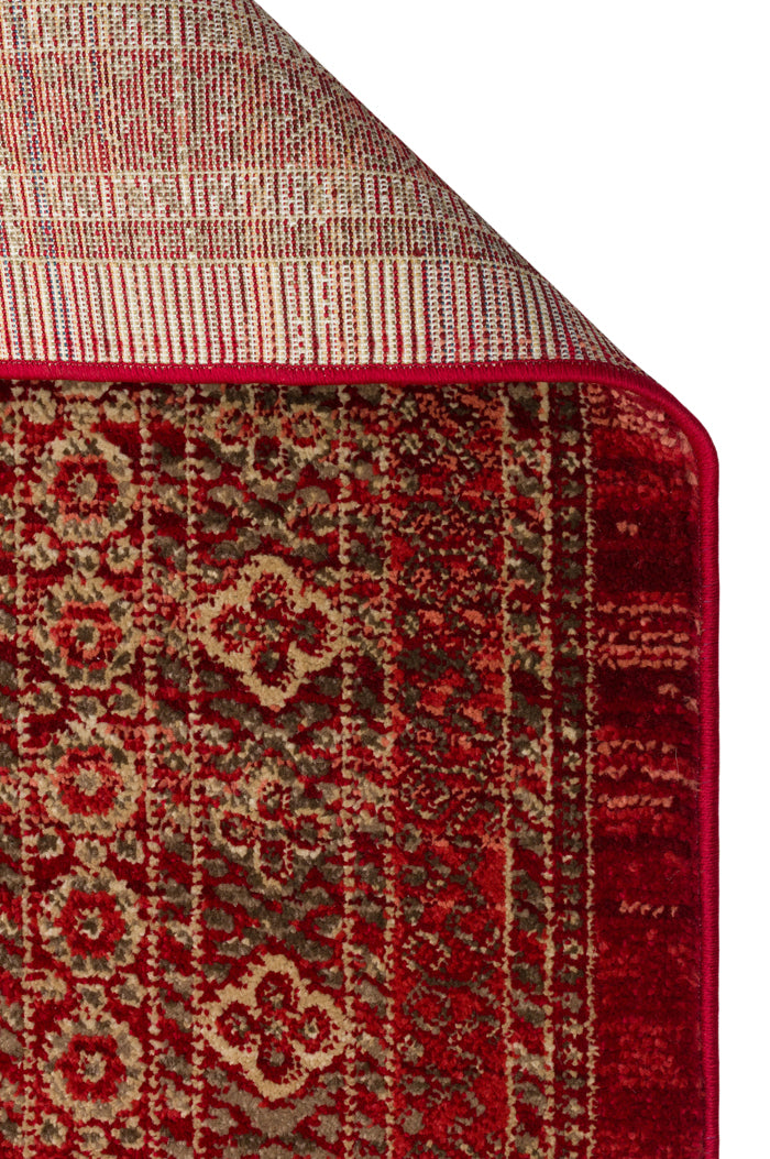 Red and beige traditional medallion pattern rug with a folded corner showing the woven backing.