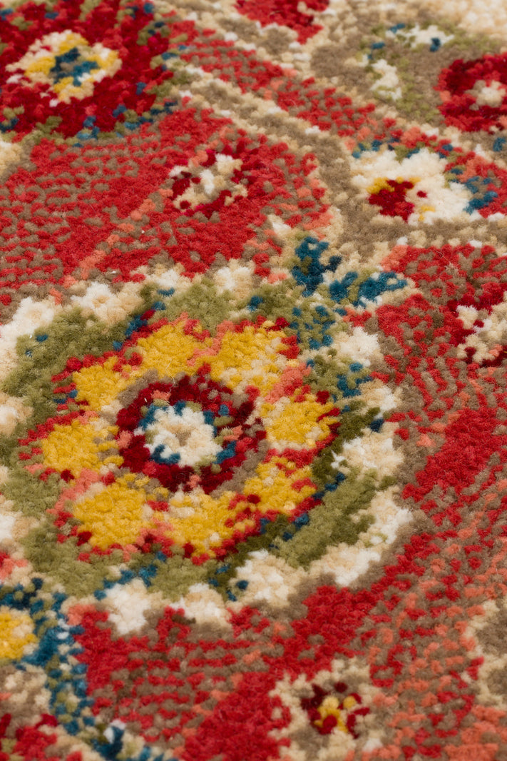 Close-up of a traditional rug with a red, yellow, green, and blue floral medallion pattern on a textured pile.