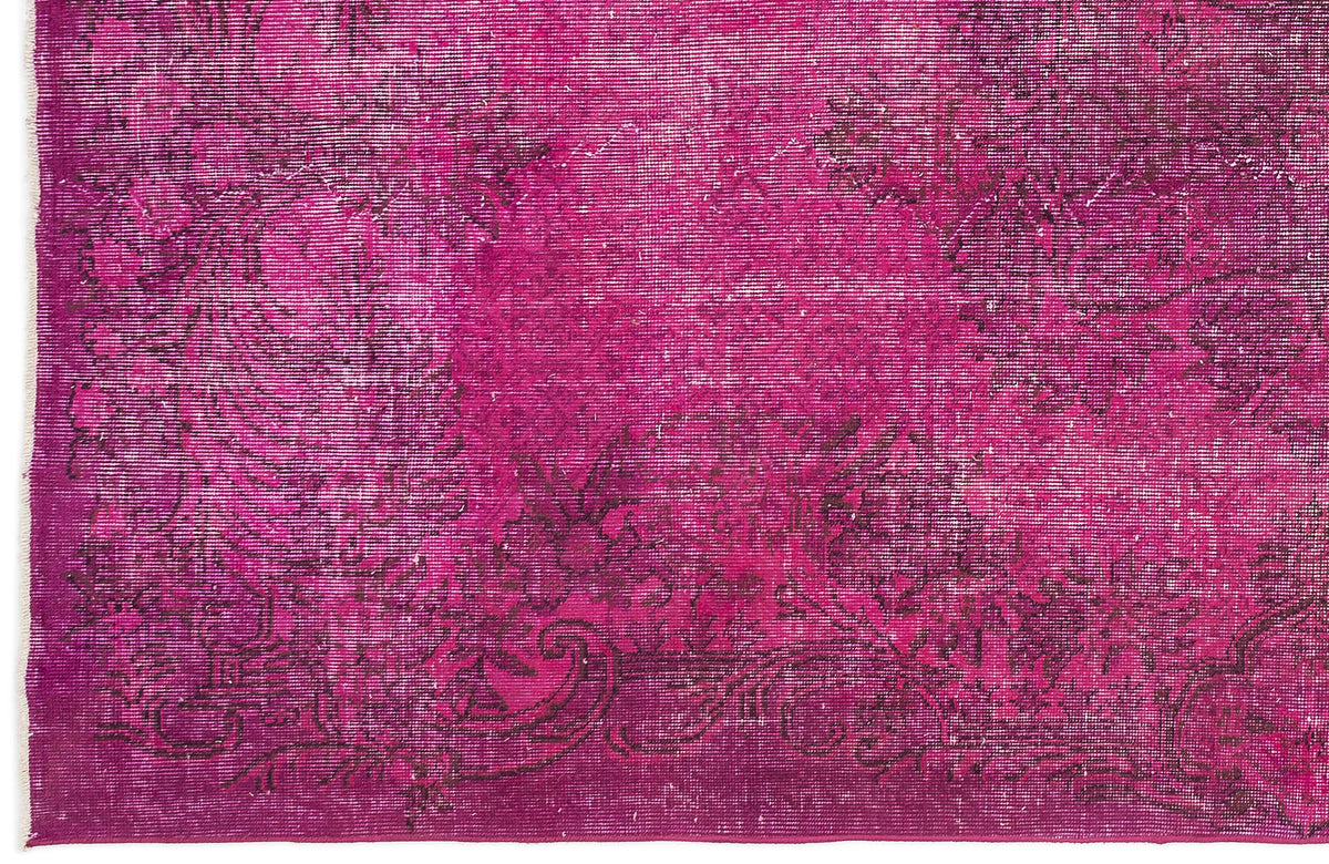 Magenta distressed rug with a dark floral medallion pattern and white fringe edge.