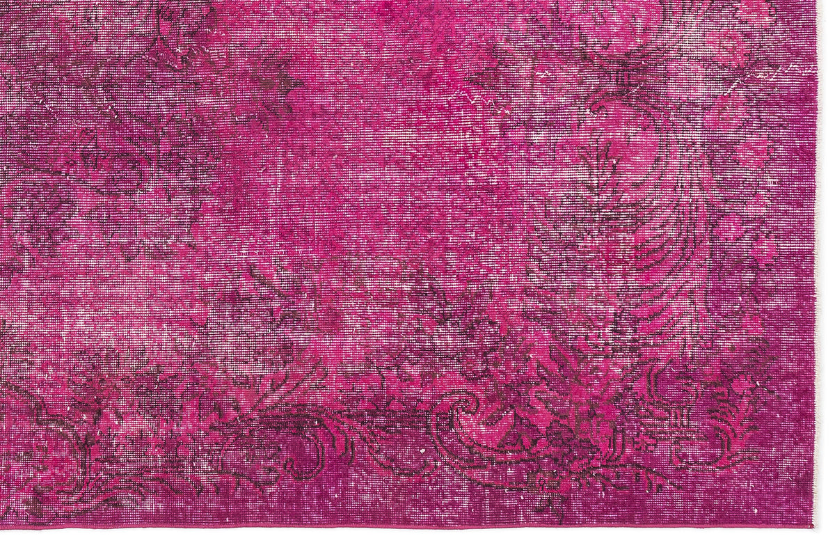 Magenta rug with a distressed, dark floral medallion pattern and a visible woven texture.