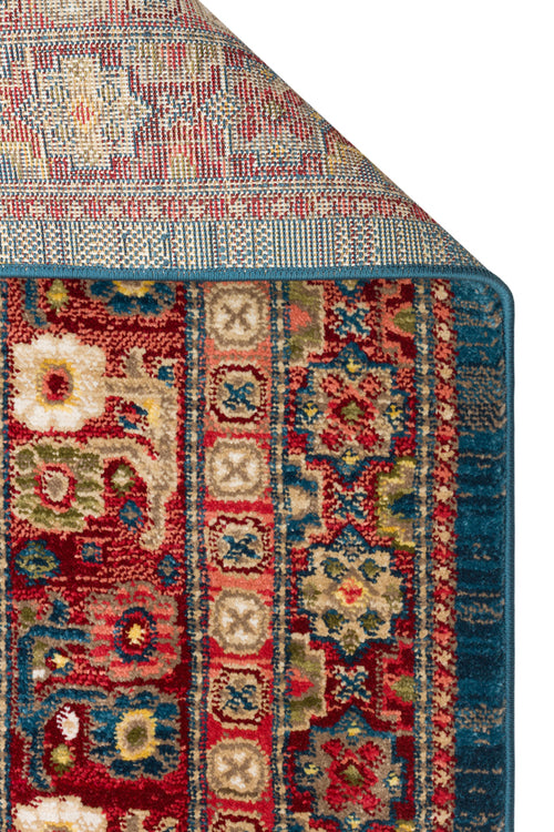 Load image 1 in gallery view. Red, blue, and beige traditional rug with a folded corner showing a floral medallion pattern and a blue serged edge.