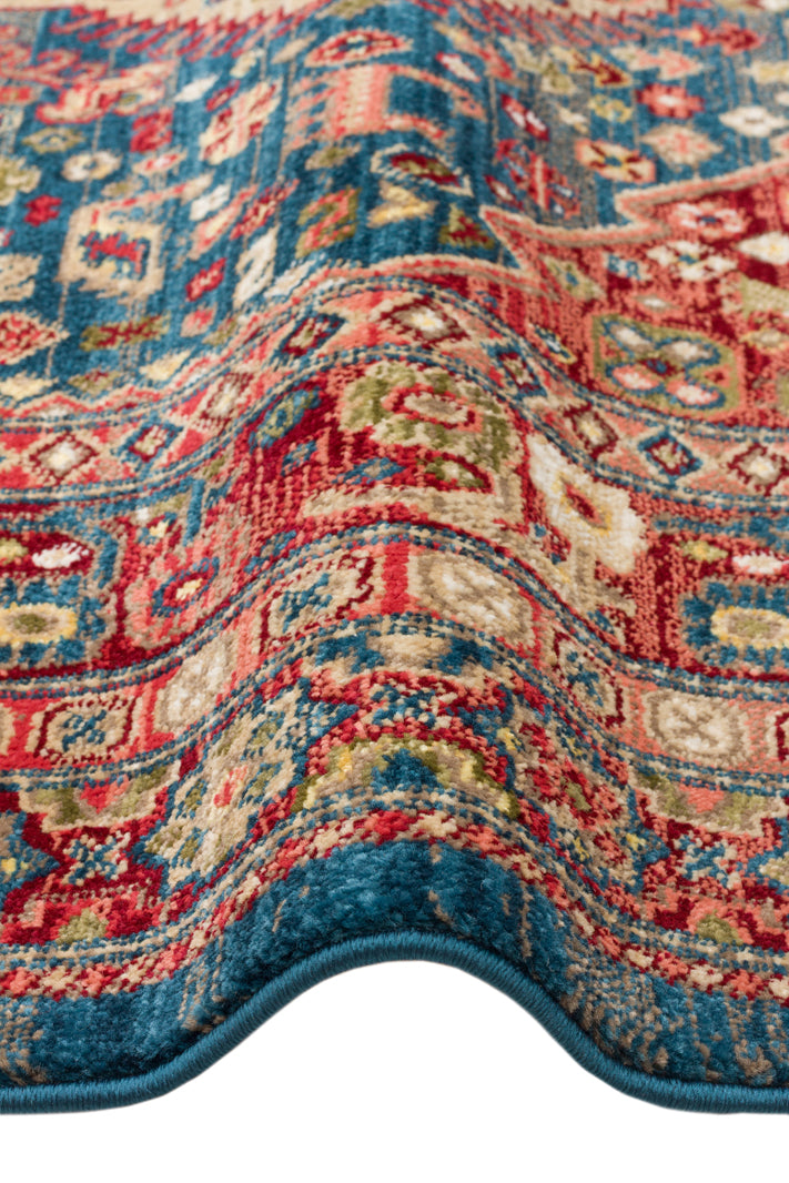 Blue and red traditional Persian-style rug with intricate floral and geometric patterns, shown folded.