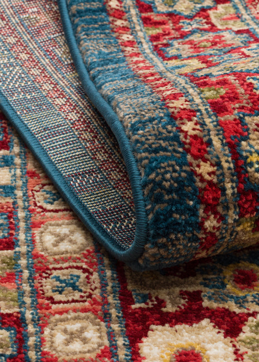 Red, blue, and beige traditional Persian-style rug with a folded corner showing a detailed geometric border.